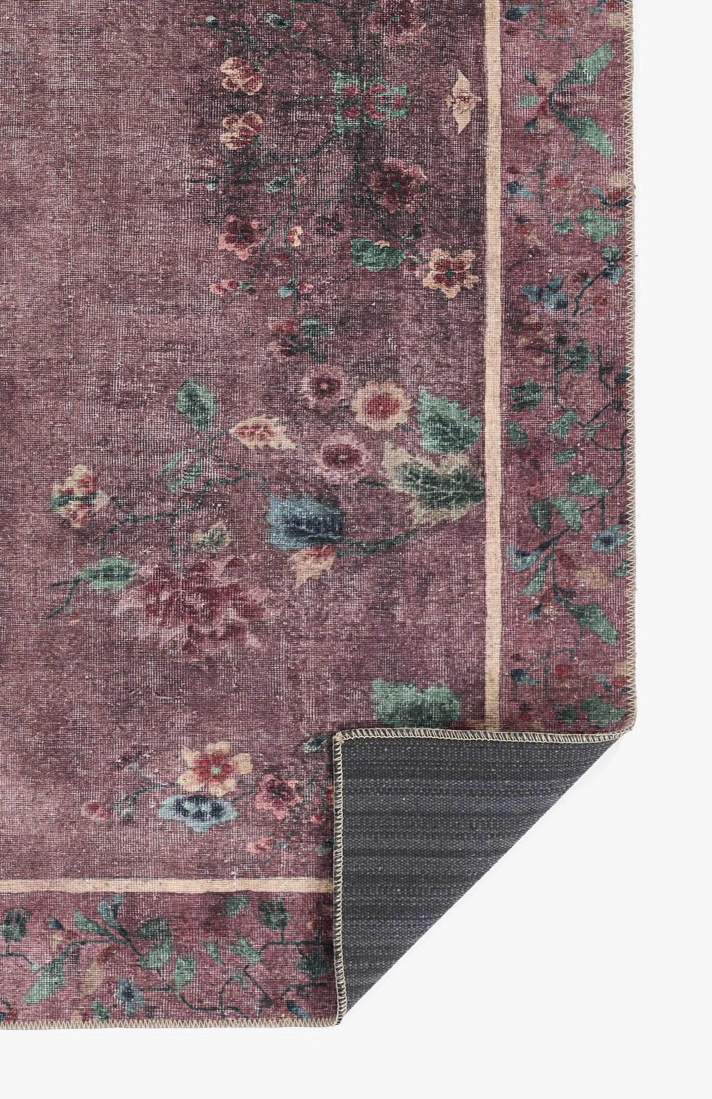 Purple floral oriental rug with green, pink & cream flowers and border; corner folded to show dark backing.