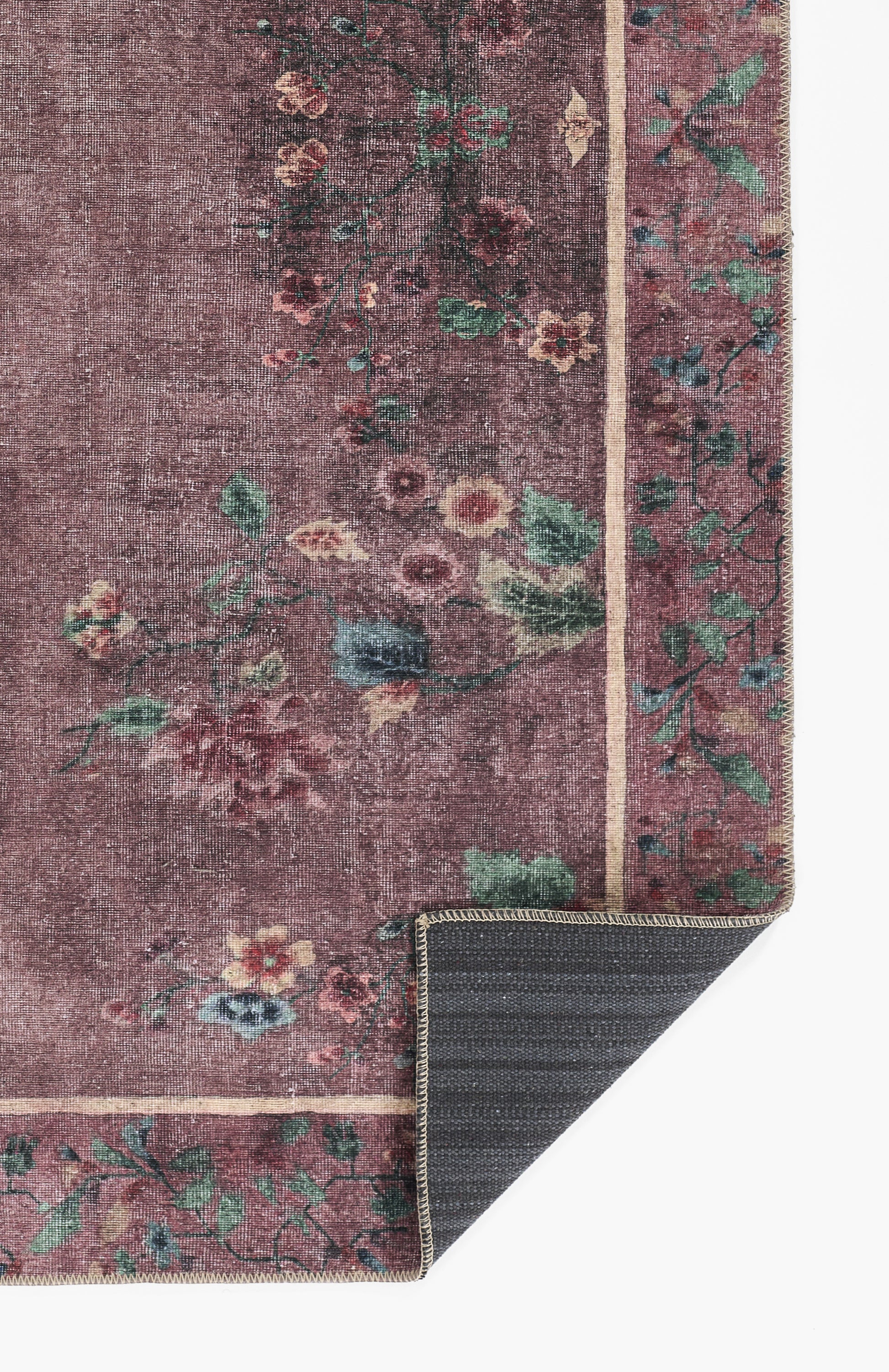 Purple floral oriental rug with green, pink & cream flowers and border; corner folded to show dark backing.