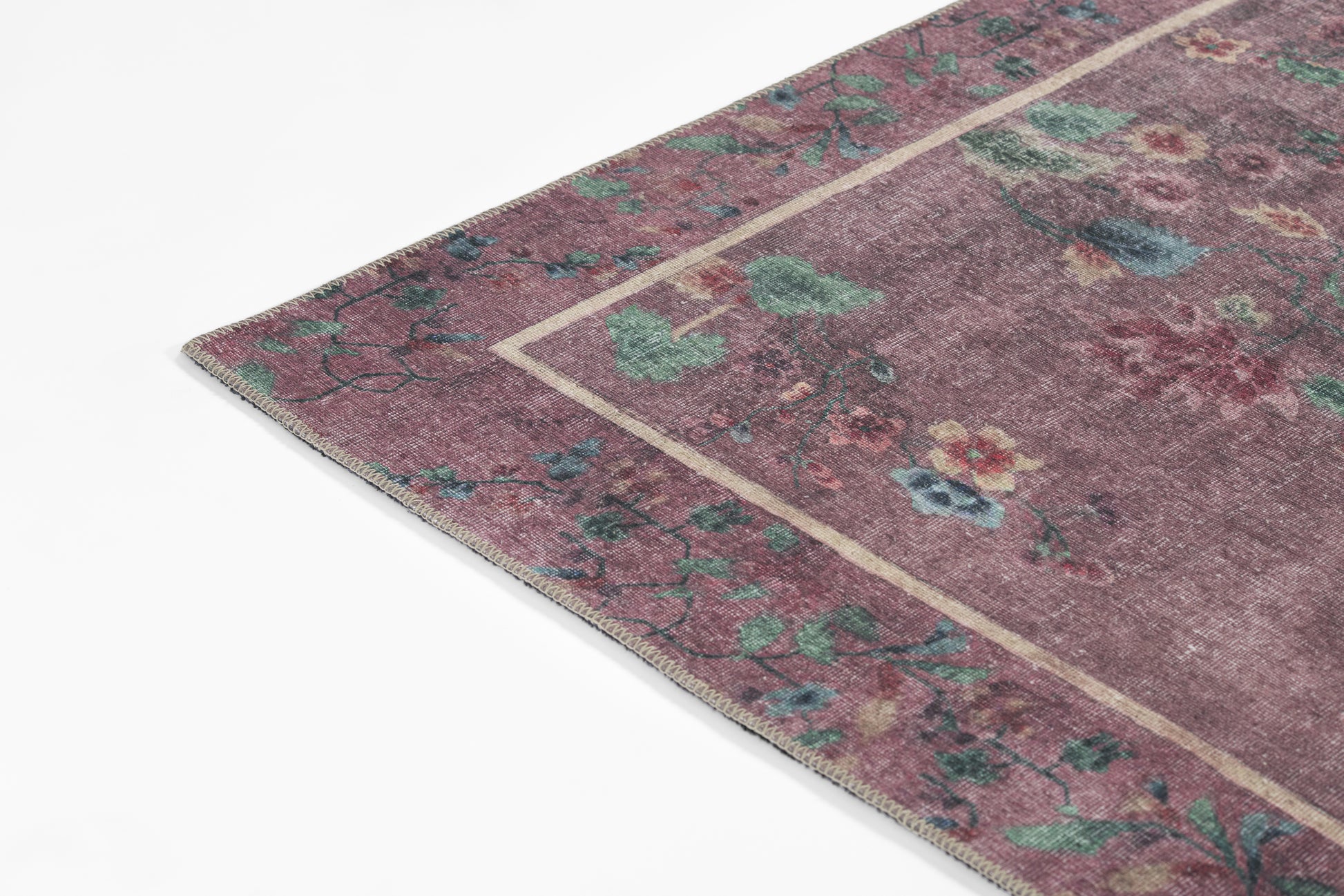 Purple oriental rug with teal and green floral motifs, beige border, corner view, soft wool feel, vintage-inspired decor.