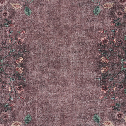 Purple distressed area rug with faded center and pink floral border with green leaves.