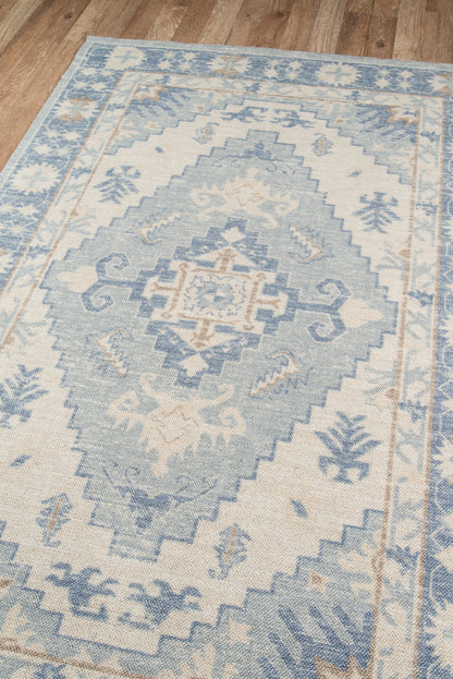 Blue and ivory Anatolian-style area rug with a large central geometric medallion on a wooden floor.