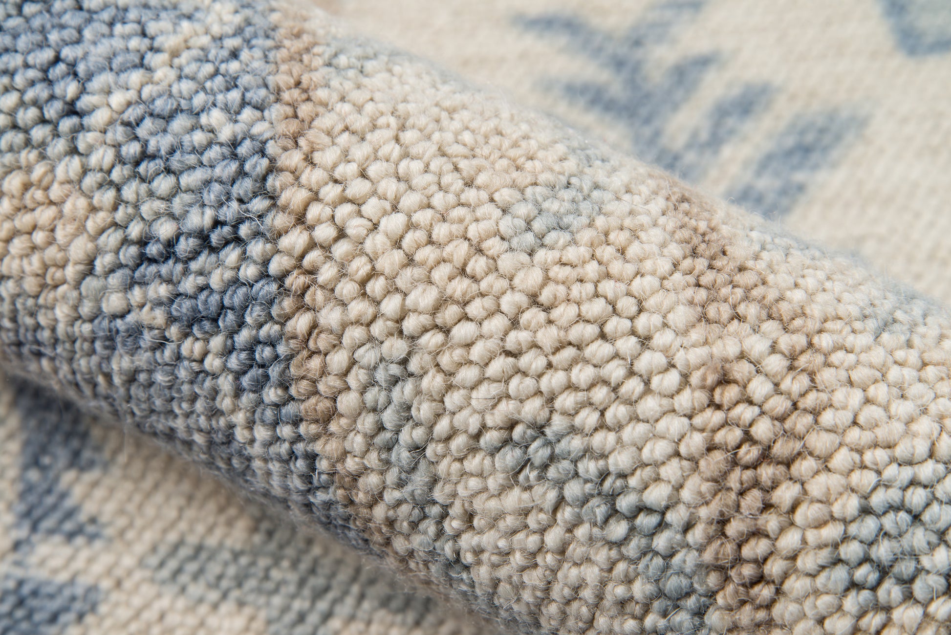 Close-up of blue-beige boucle rug with dense loop pile and rolled edge.