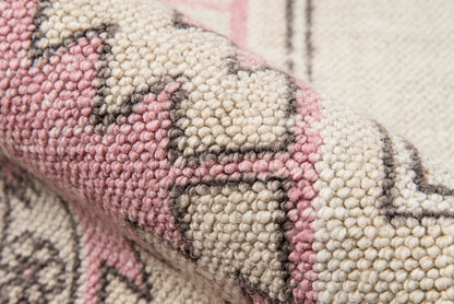Close-up of pink and cream wool rug with geometric tribal motifs and chunky boucle weave.