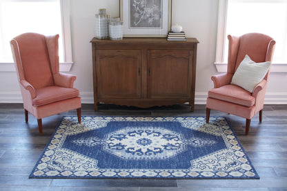 Two coral upholstered wingback chairs flank a dark wood sideboard over a blue & cream oriental rug.