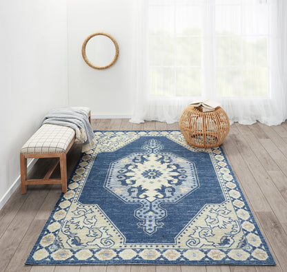 Navy blue and ivory oriental-style area rug with central medallion on wooden floor; bench and wicker stool nearby.