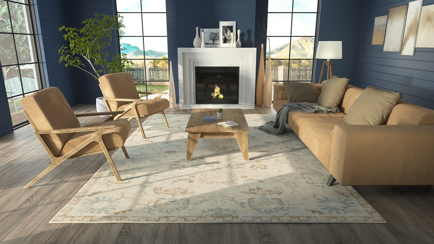 Modern living room with blue walls, tan leather chairs, beige sofa, wooden coffee table, fireplace, plant, and patterned rug.