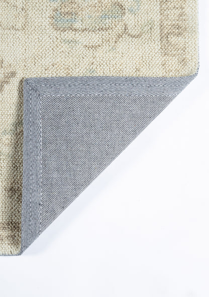 Beige patterned area rug with blue denim-style folded corner showing underside and stitching.