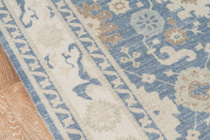 Blue & cream rectangular oriental-style rug with ornate floral patterns on a wooden floor.