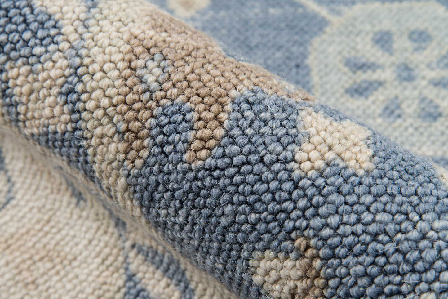 Close-up of a blue and beige tufted rug with textured looped pile and geometric pattern.