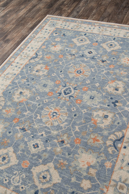 Blue floral area rug with ivory border, soft woven texture, geometric medallions & peach accents on a wooden floor.