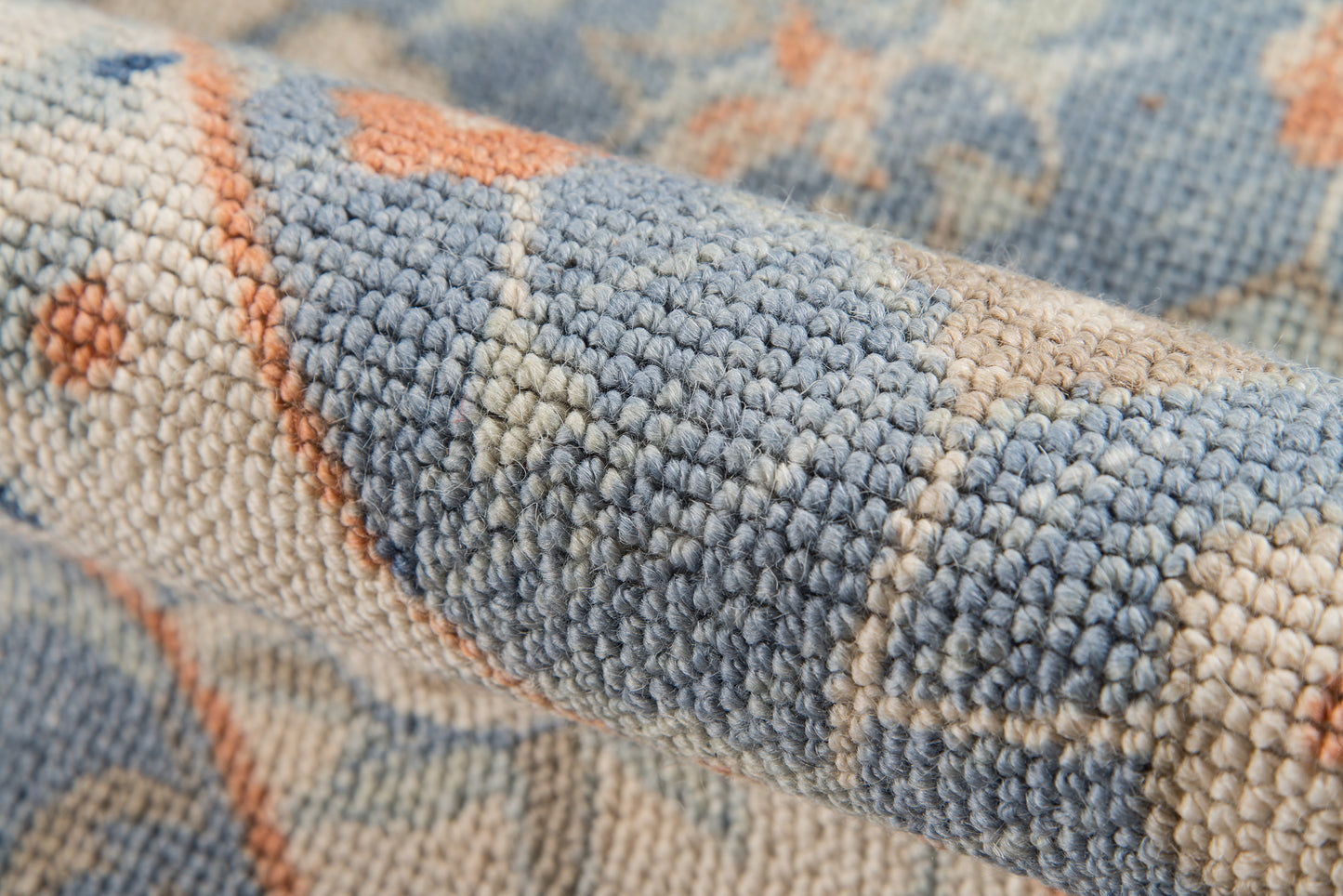 Close-up of a blue & beige woven rug with a geometric pattern & chunky textured loop pile.