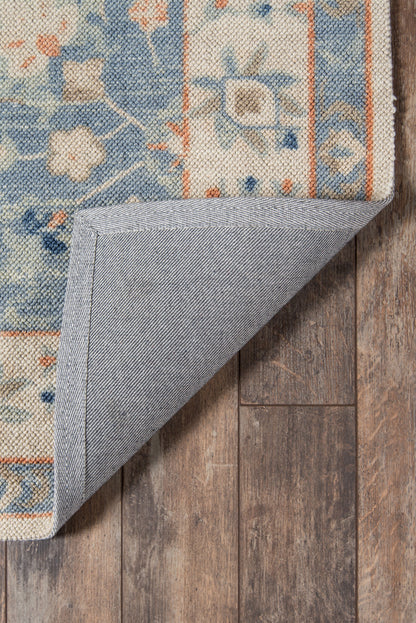 Blue floral oriental area rug with orange border, folded corner reveals grey backing on wood floor.