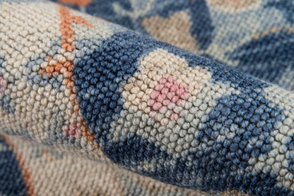 Close-up of a tufted wool rug in blue, navy, cream and pink geometric pattern; chunky pile.