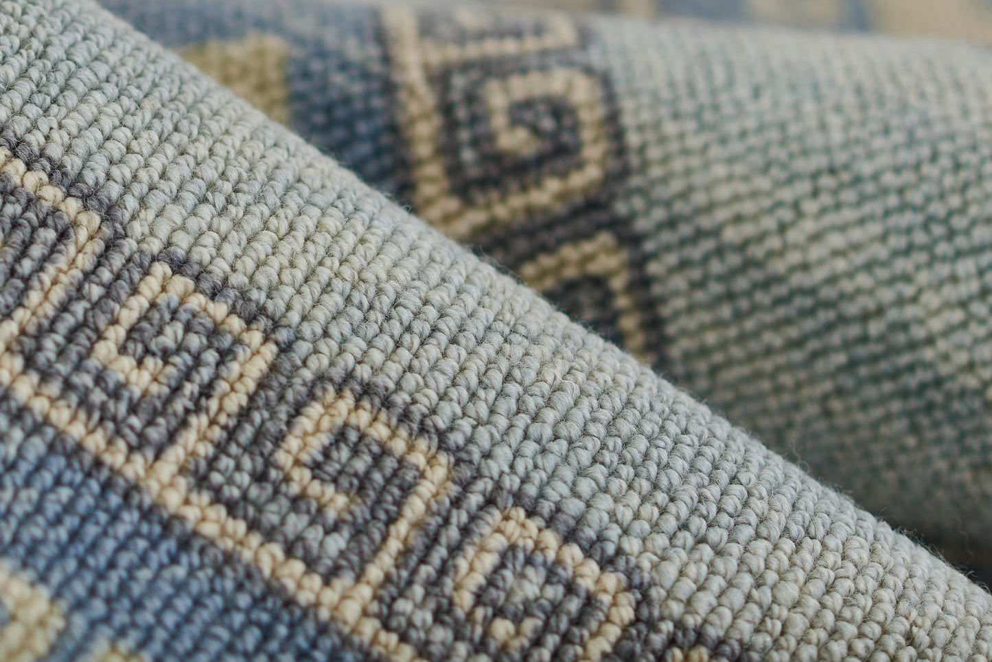 Blue-gray woven textile with beige geometric Greek-key border; thick, textured fabric.