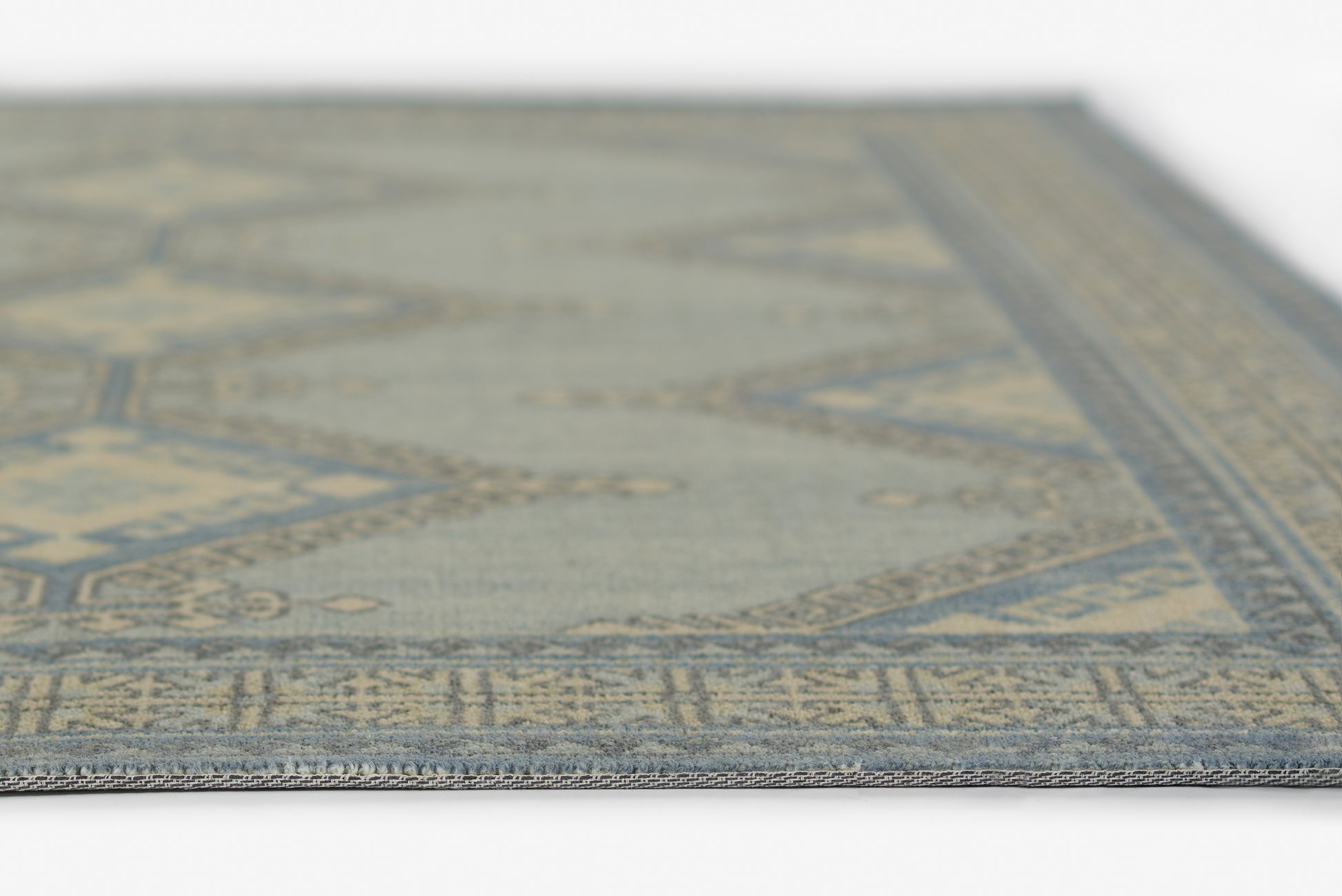 Blue and beige geometric area rug with decorative border; close-up view.