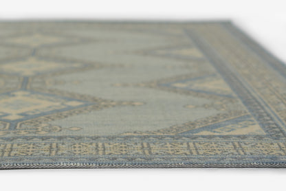 Blue-gray oriental rug with geometric border; close-up view of woven edge.