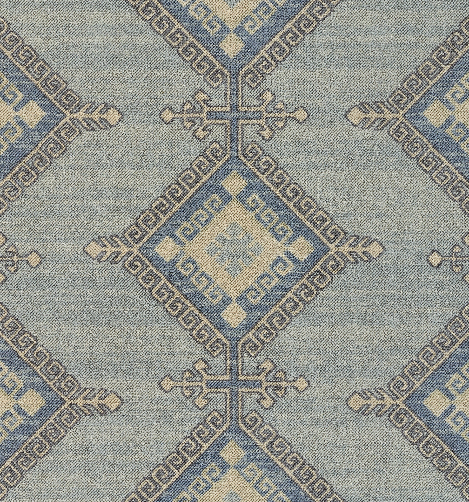 Blue woven textile with ivory geometric diamonds and Greek-key borders in a repeating pattern.