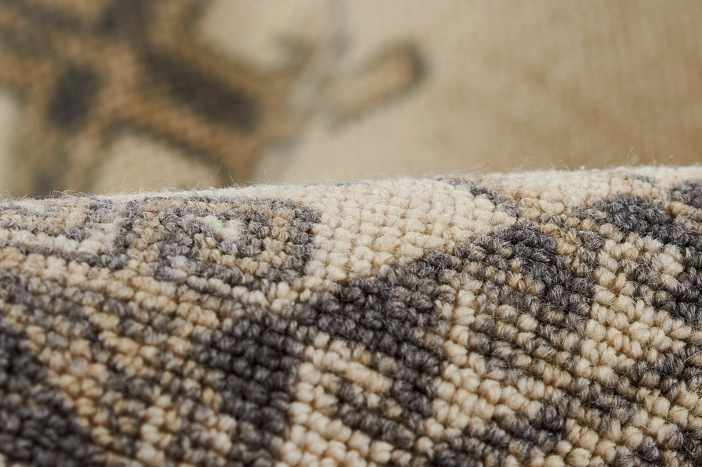 Close-up of beige, ivory and charcoal Anatolian wool rug with geometric pattern and soft woven pile.