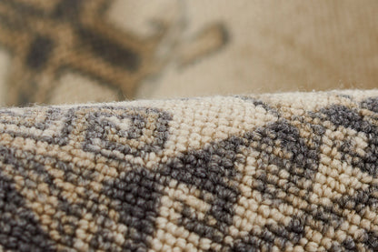 Close-up of beige and charcoal woven rug with geometric diamond pattern.