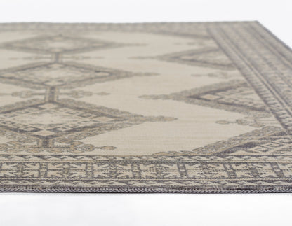 Beige rectangular rug with gray geometric tribal motifs and decorative border; flatwoven style, ideal for living room.