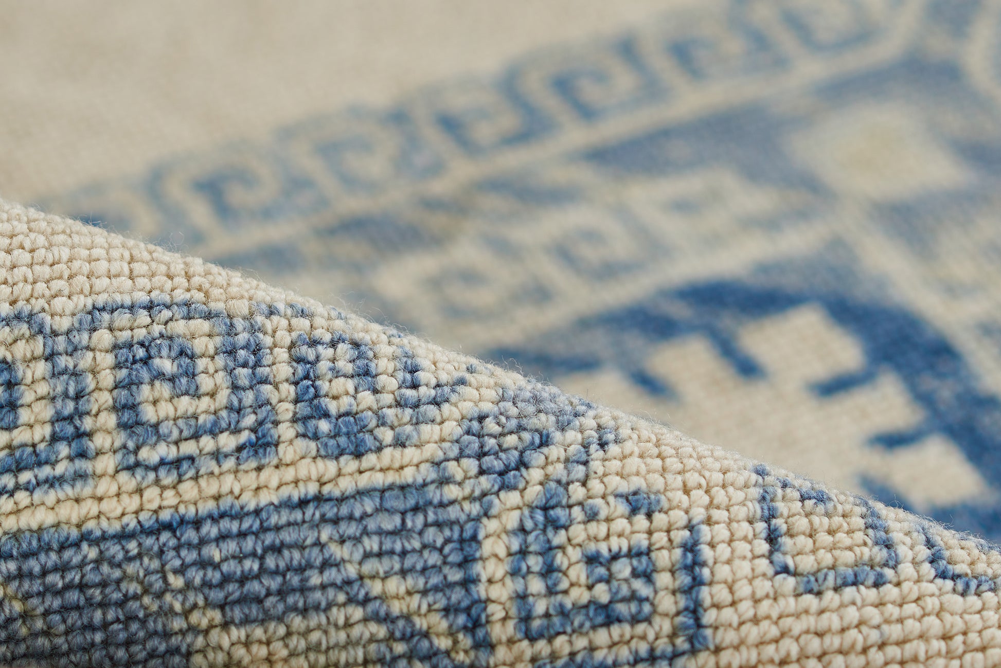 Close-up of blue and ivory woven rug with geometric patterns and soft textured pile.