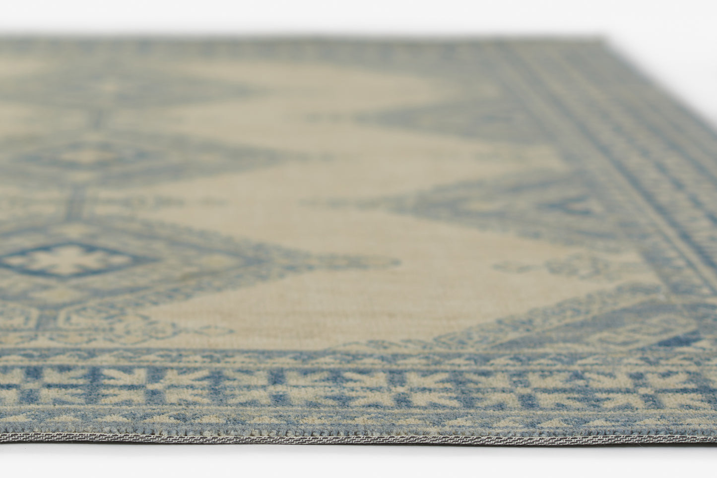 Close-up of a blue and ivory woven rug with a geometric border, oriental-style home decor.