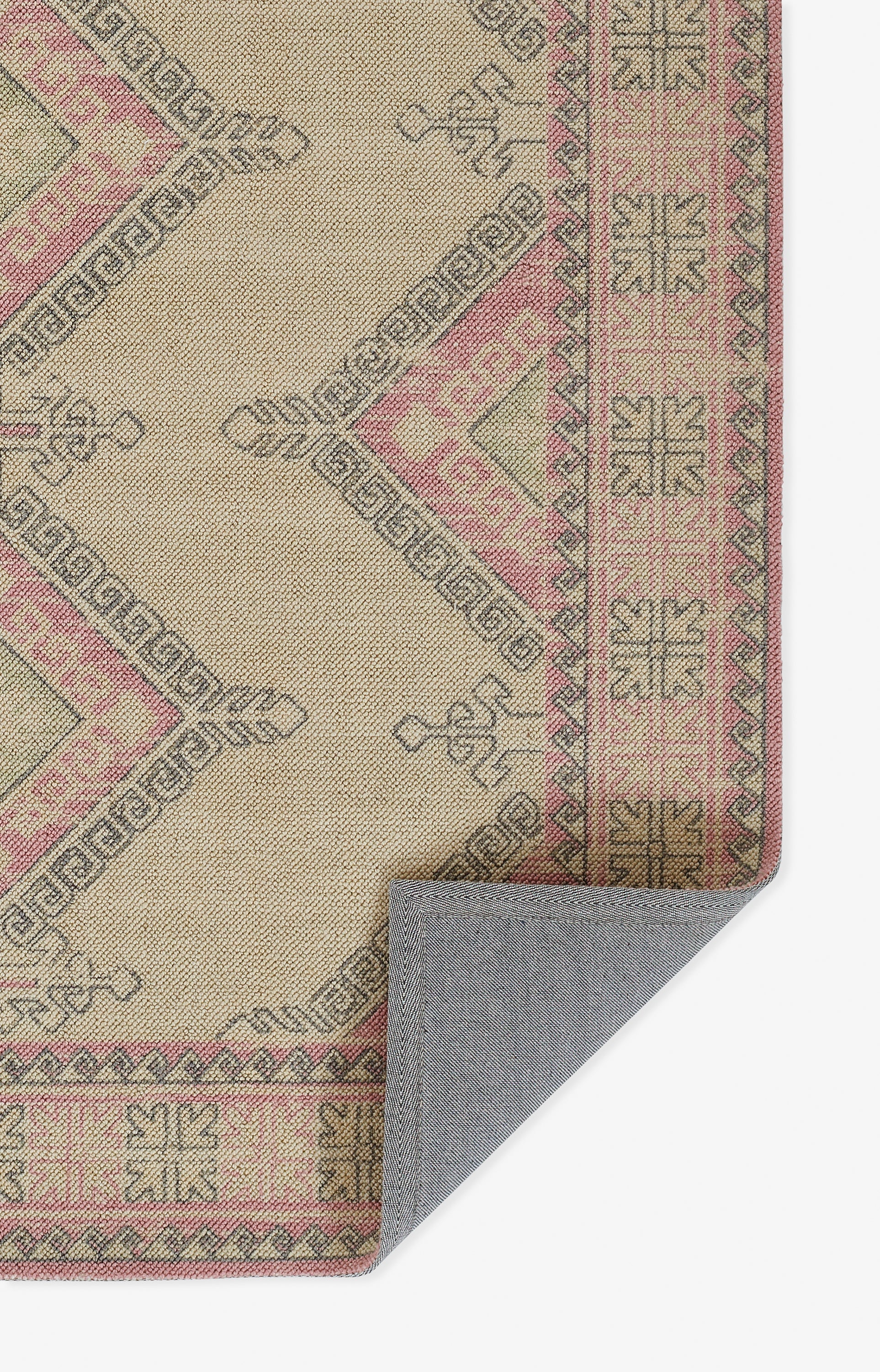 Beige woven rug with pink geometric tribal border and light brown detailing; folded gray underside visible.
