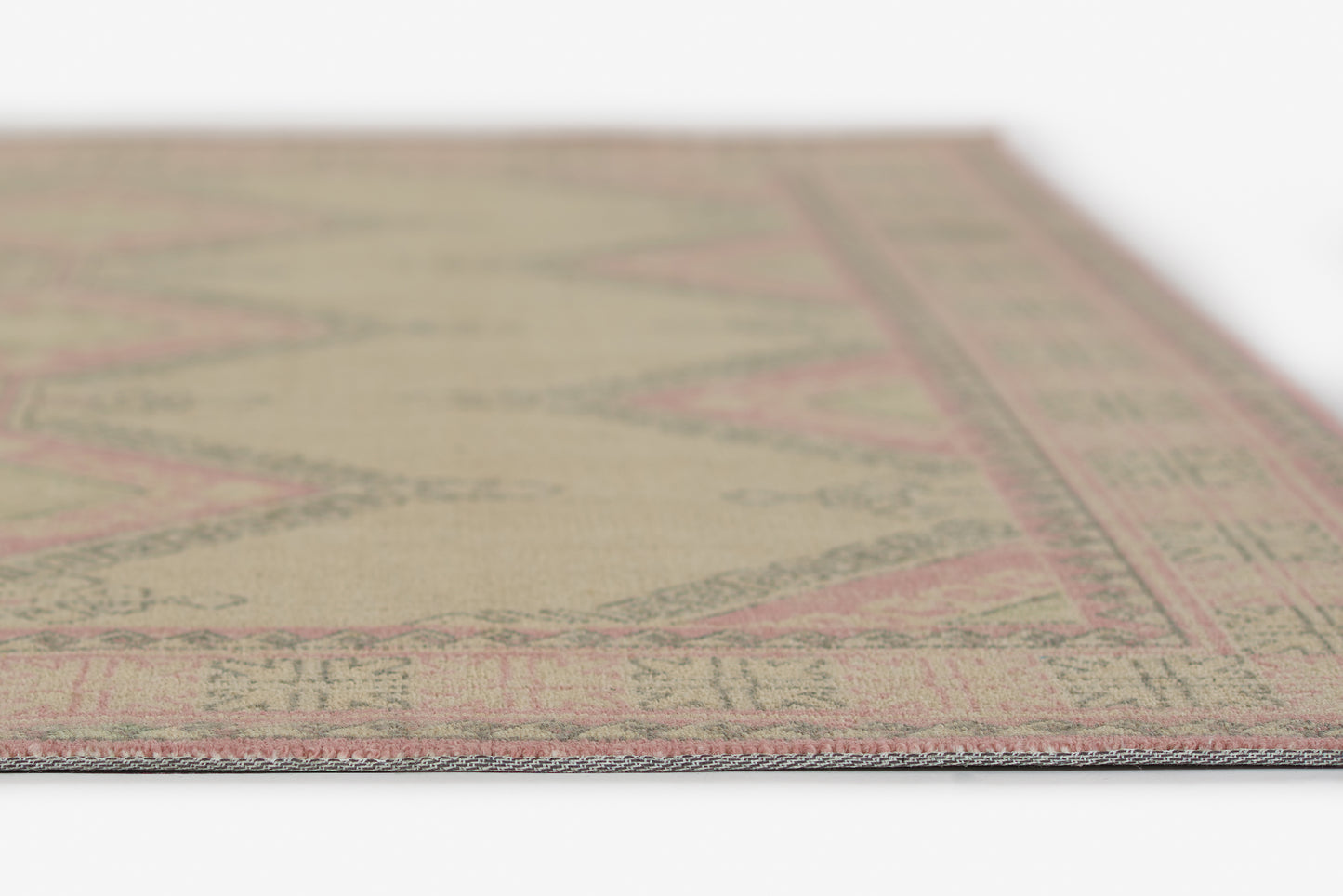 Beige flatwoven rug with pink geometric diamonds and pink border; rectangular, low-pile, boho style.