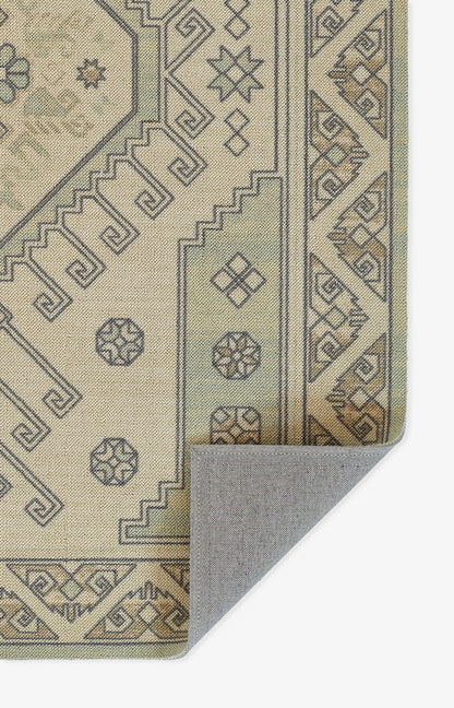 Beige geometric rug with grey-brown outlining, Greek-key borders; folded corner shows backing.