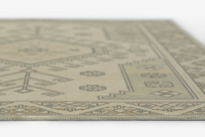 Beige flat-weave rug with brown geometric border and central motifs; rustic, contemporary décor.