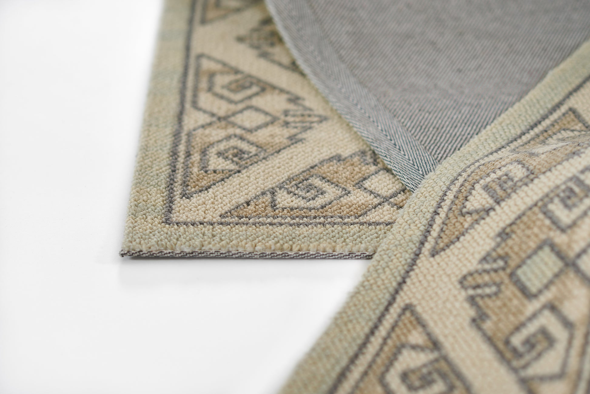 Beige woven rug runner with taupe geometric tribal border on white surface.