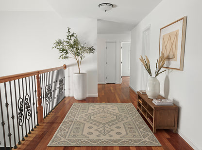 Bright hallway with hardwood floor, beige patterned rug, potted plant, wrought-iron railing, wooden console with vase & stems