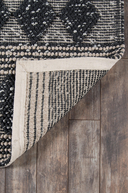 Boho tribal runner rug with black diamond motifs on cream woven texture; folded corner reveals striped underside on wooden floor.