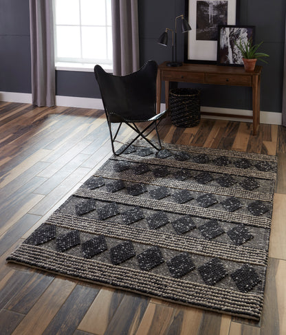 Charcoal gray area rug with a diamond pattern on a dark wood floor in a modern living room.