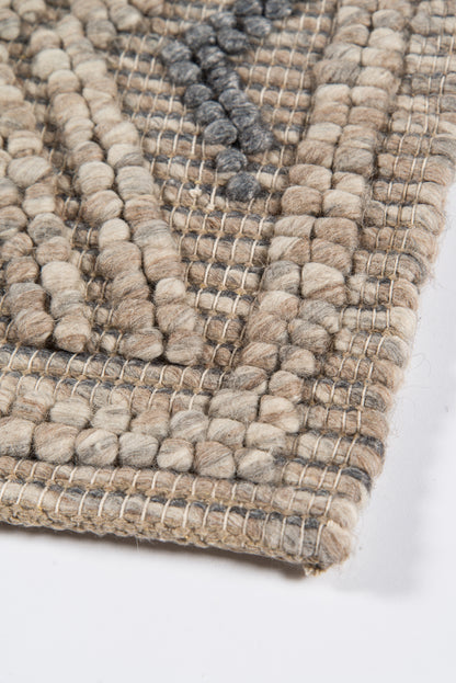 Beige and gray chunky woven rug with looped wool tufts and a geometric diamond pattern, textured and rectangular.