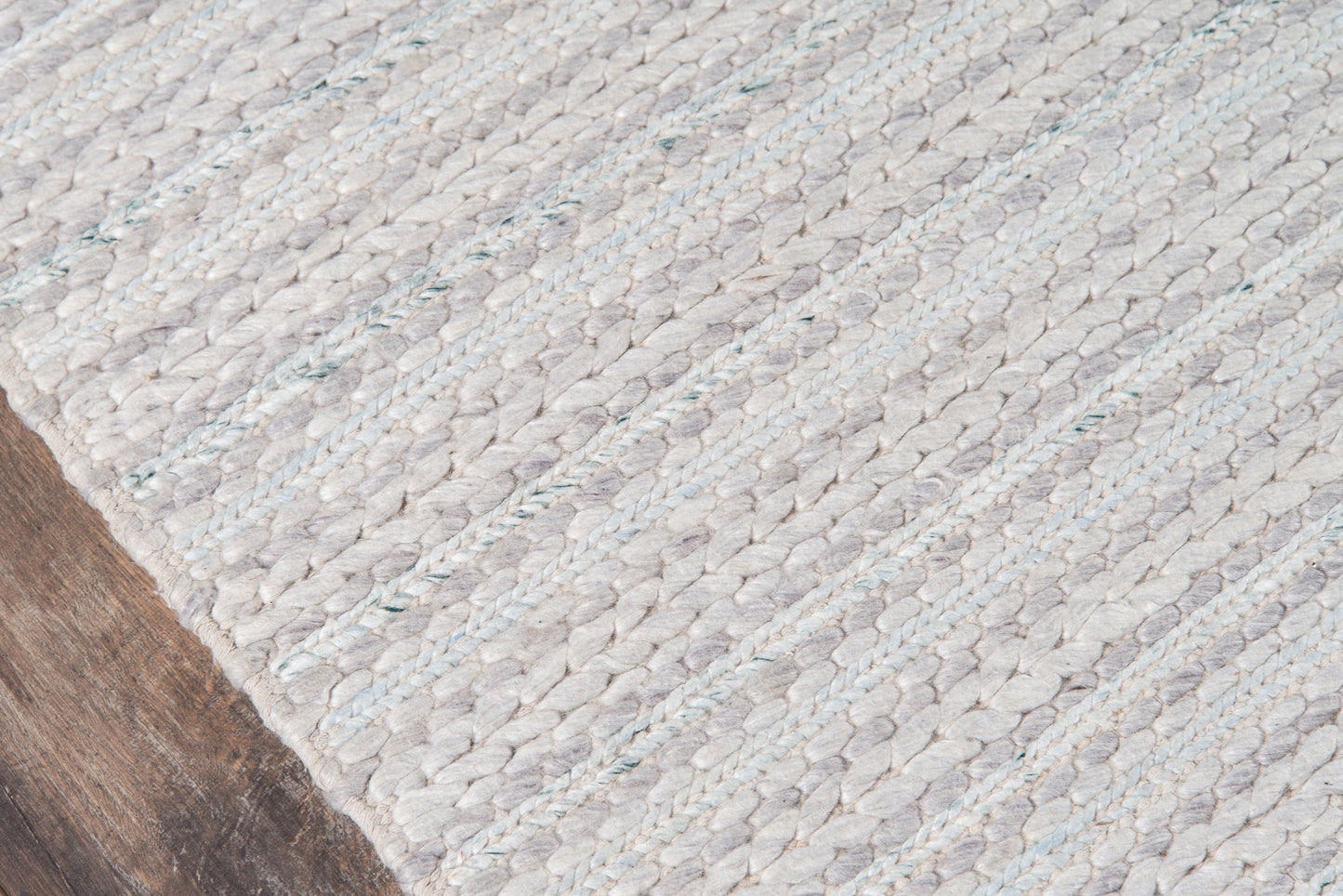 Close-up of a light gray natural-fiber woven runner with a chunky braided texture on a wood floor.