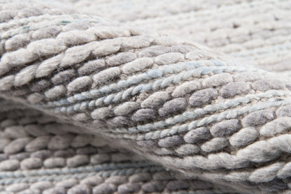 Close-up of a chunky braided boucle rug in soft Andes Sand gray-beige tones.