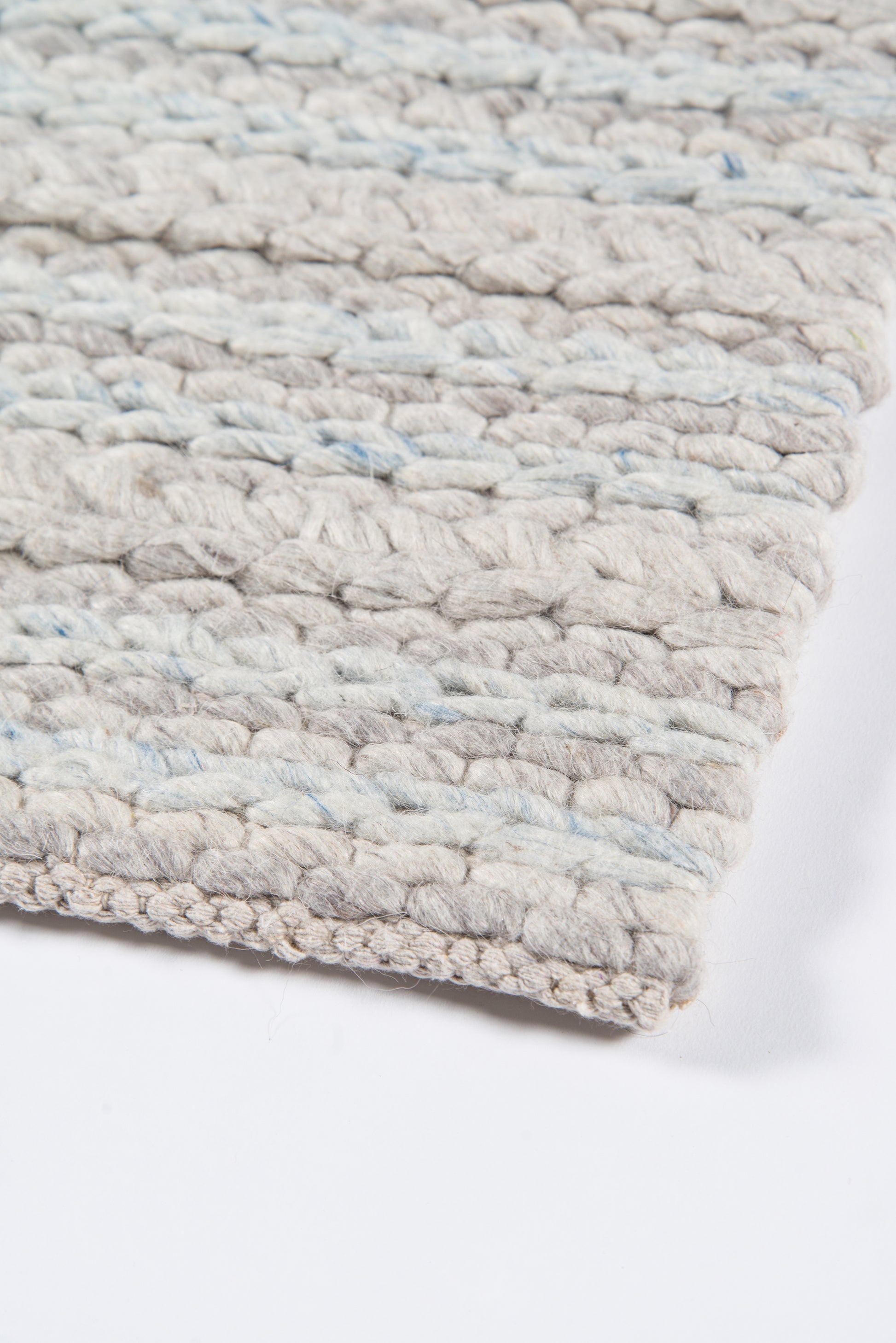 Beige chunky woven rug with pale blue flecks, close-up textured loops.