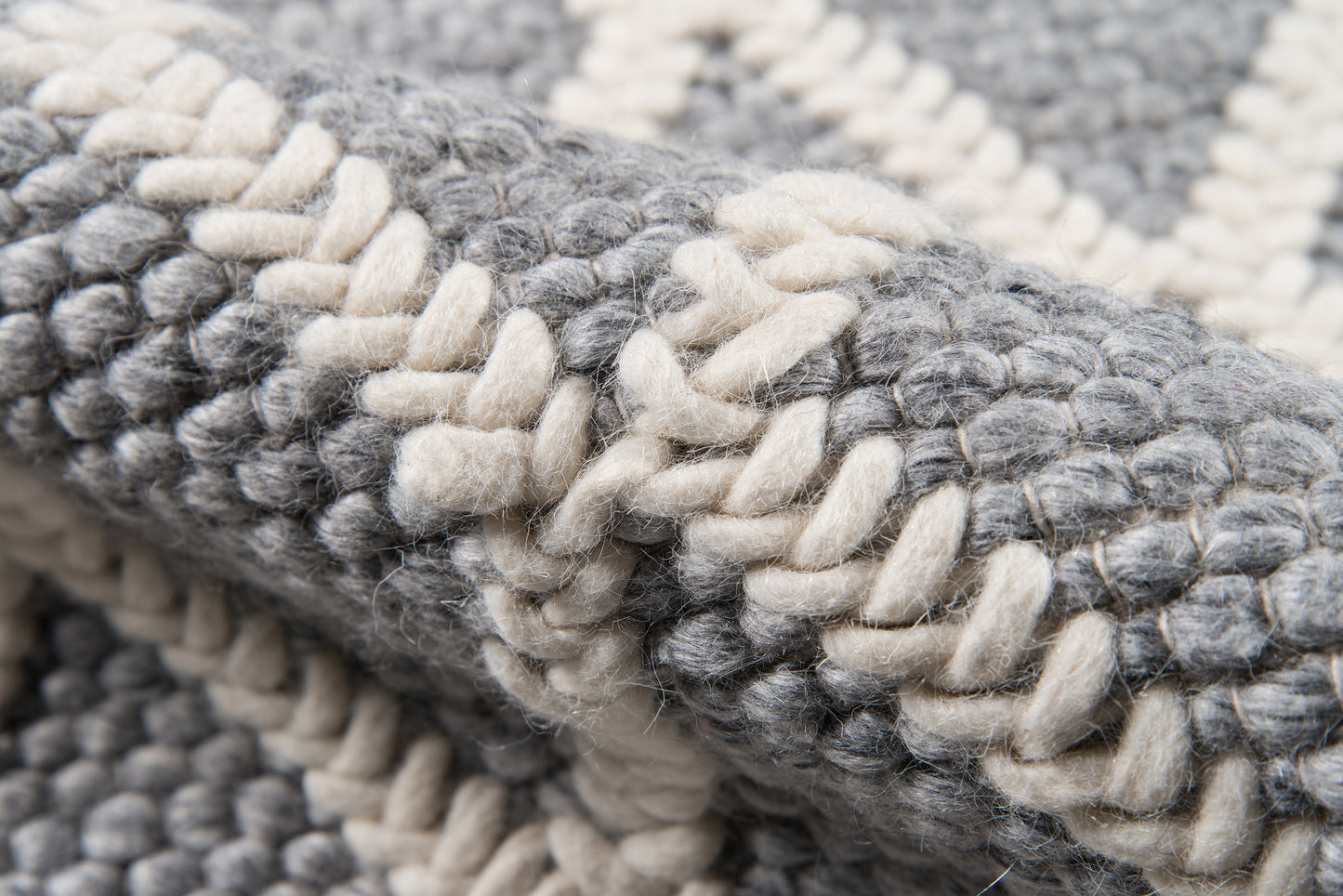 Close-up of a chunky woven rug in gray and cream with thick looped yarn and striped pattern.