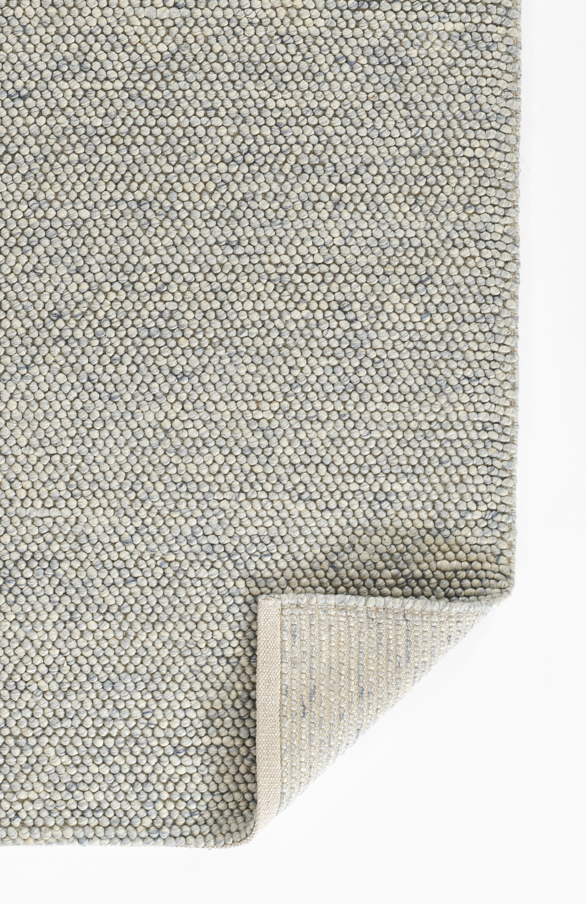 Light blue-grey boucle rug with tight pebble-like loops, rectangular with folded corner showing underside.
