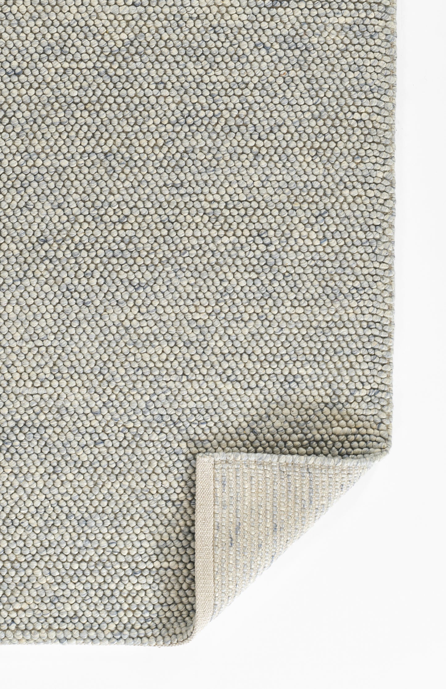 Pebble-textured gray-blue rug with tiny loop fibers, folded corner showing underside.