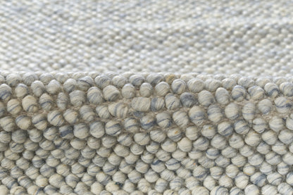 Close-up of a gray-blue boucle rug with chunky looped yarn and a soft, textured weave.