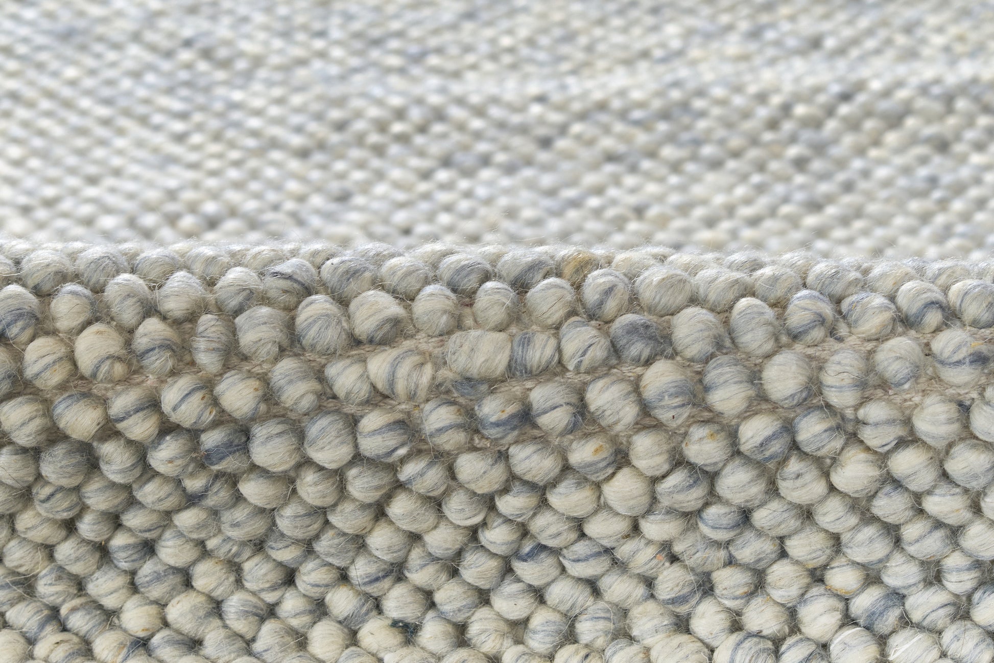 Close-up of a grey-blue boucle rug with dense looped pile; textured, cozy, modern home decor.