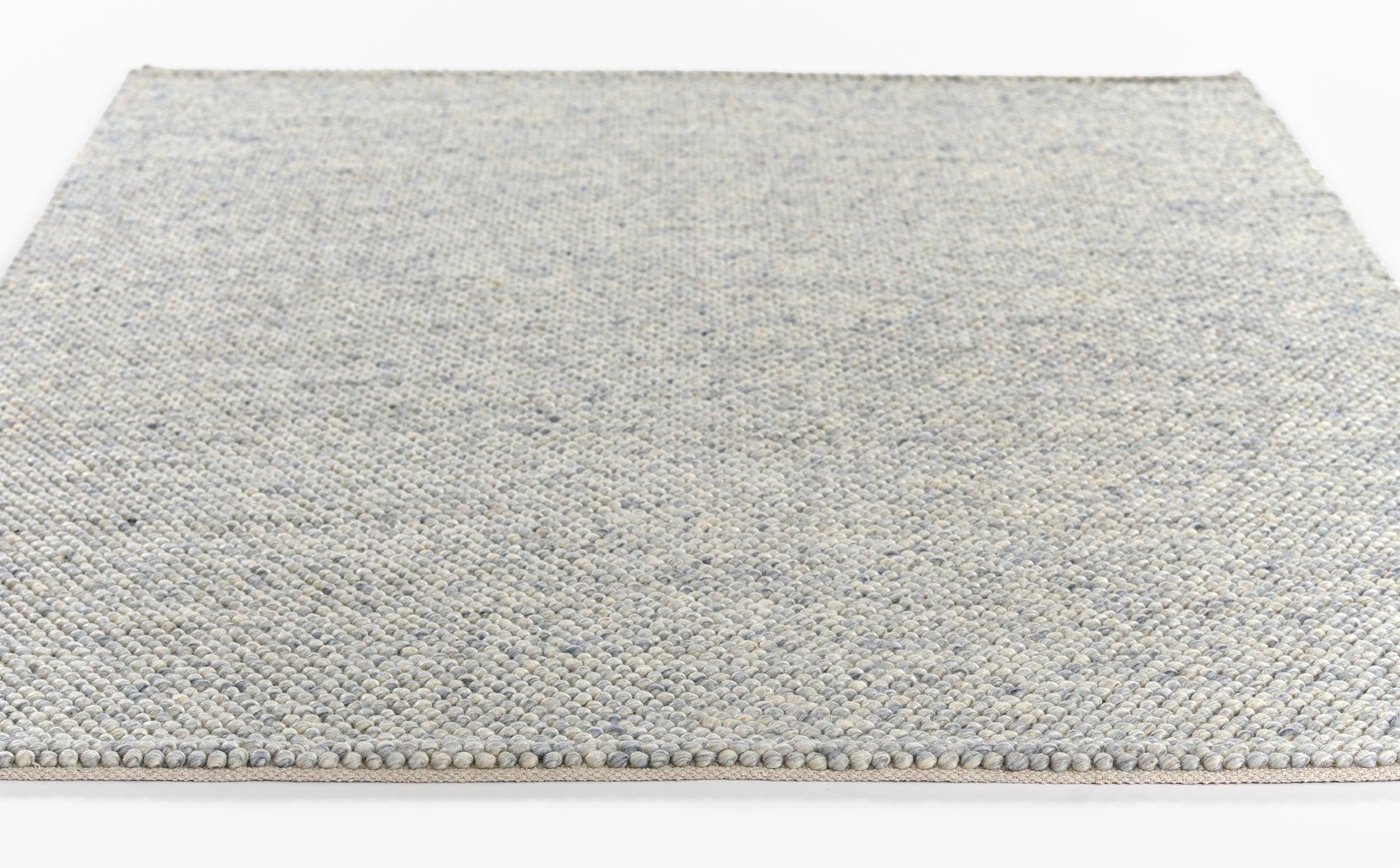 Rectangular flat-weave rug in light blue-gray with speckled texture and tassel fringe along the edge.
