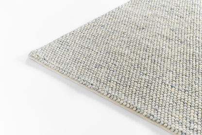 Close-up of a blue-gray speckled, flat-weave rug with beige edge binding; contemporary area rug.