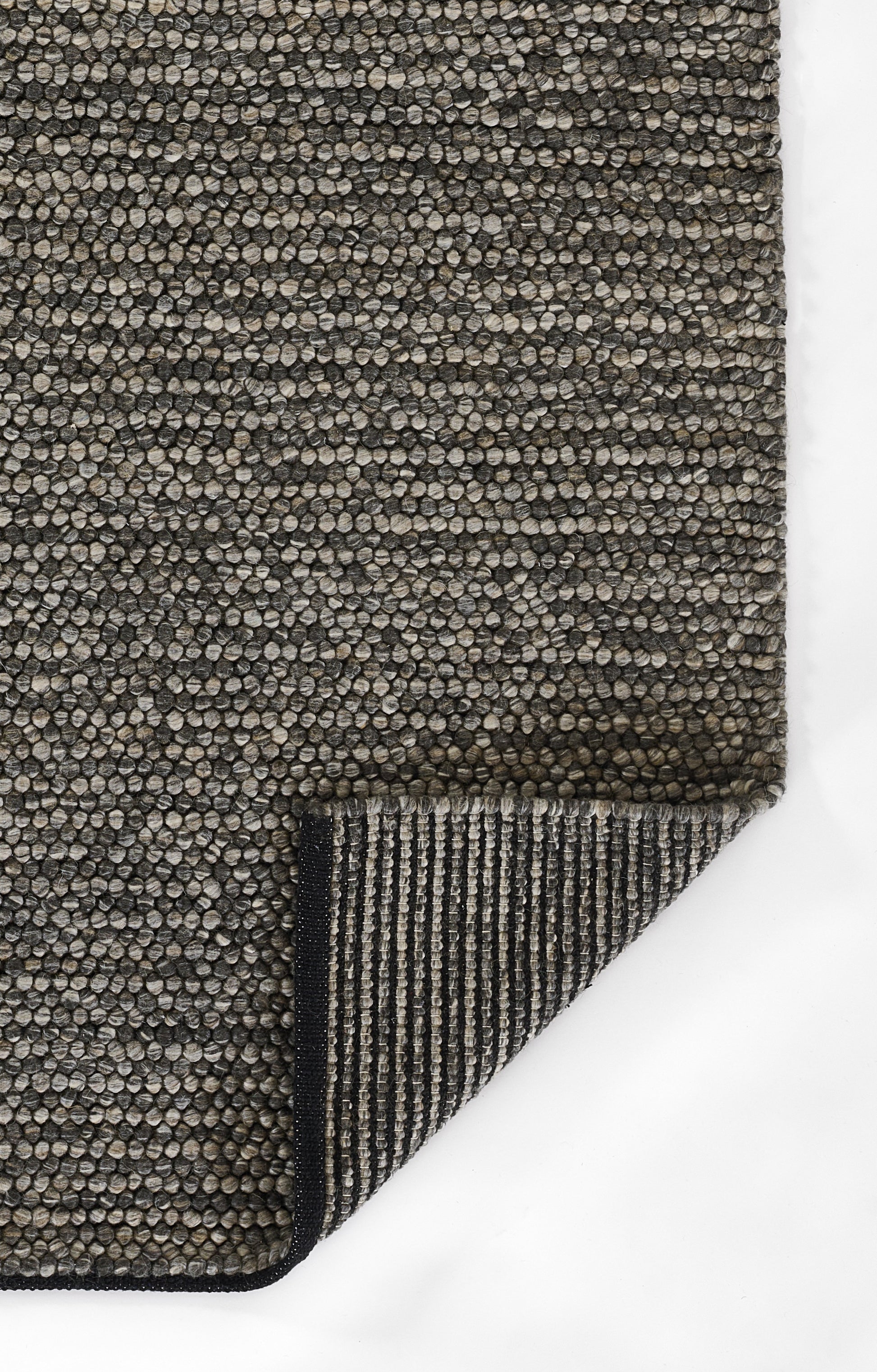 Taupe and charcoal textured woven rug with pebble loop pattern; folded corner reveals striped underside.
