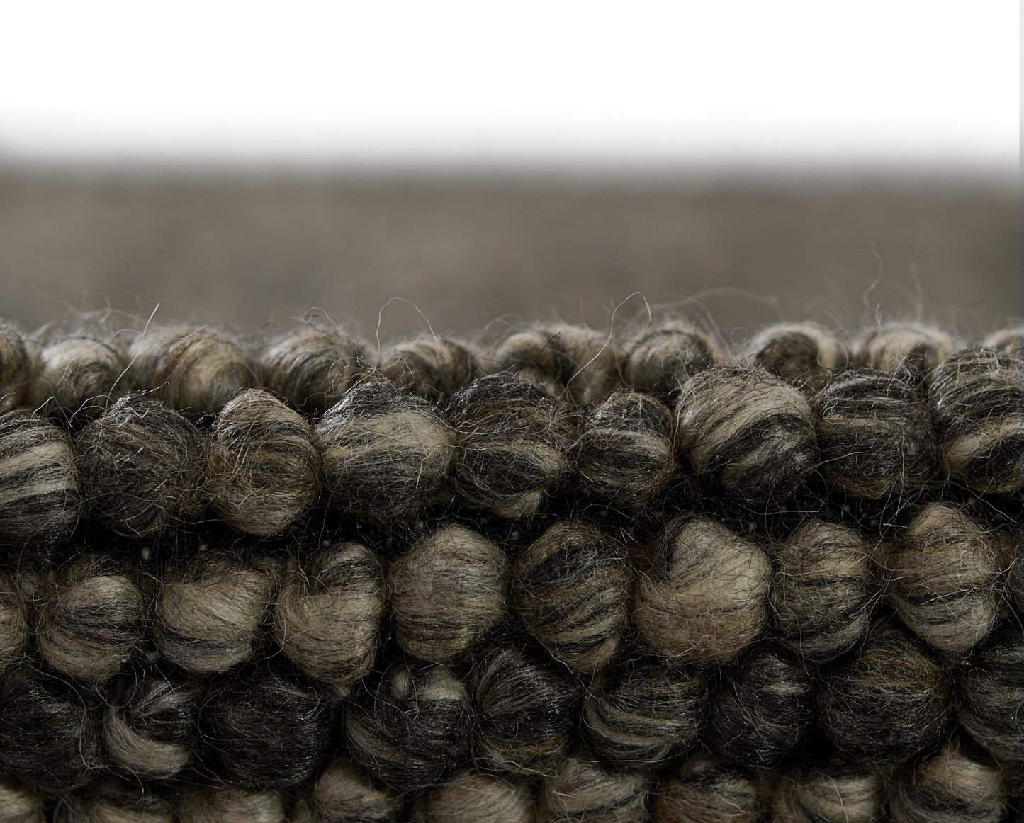 Dark brown and gray chunky wool rug with thick looped pile and braided texture.