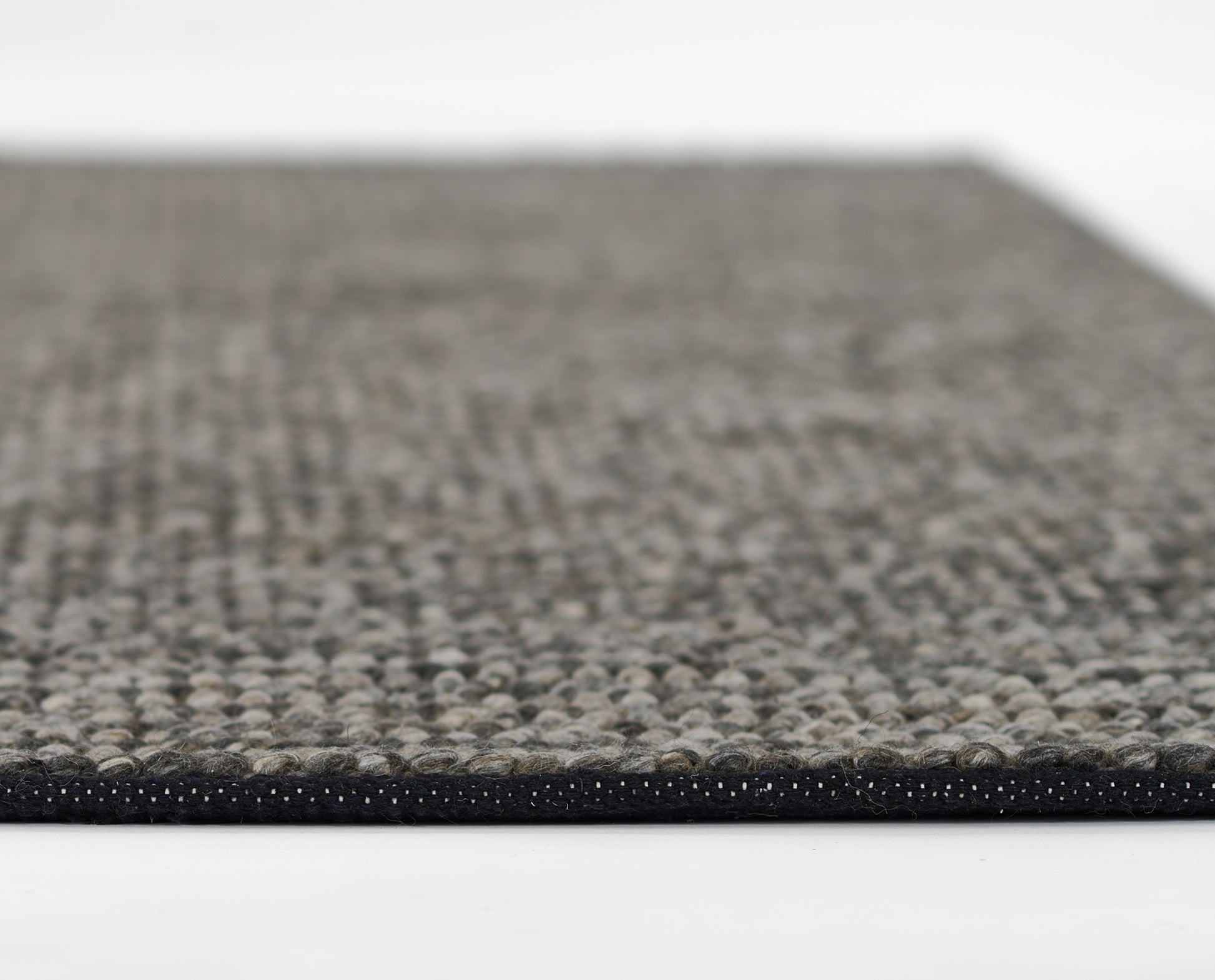 Beige and charcoal speckled low-pile area rug with black edge binding; modern, versatile runner.