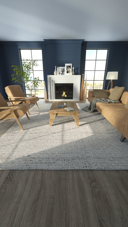 Light gray woven area rug with subtle texture under a wooden coffee table in a navy living room with tan sofa.
