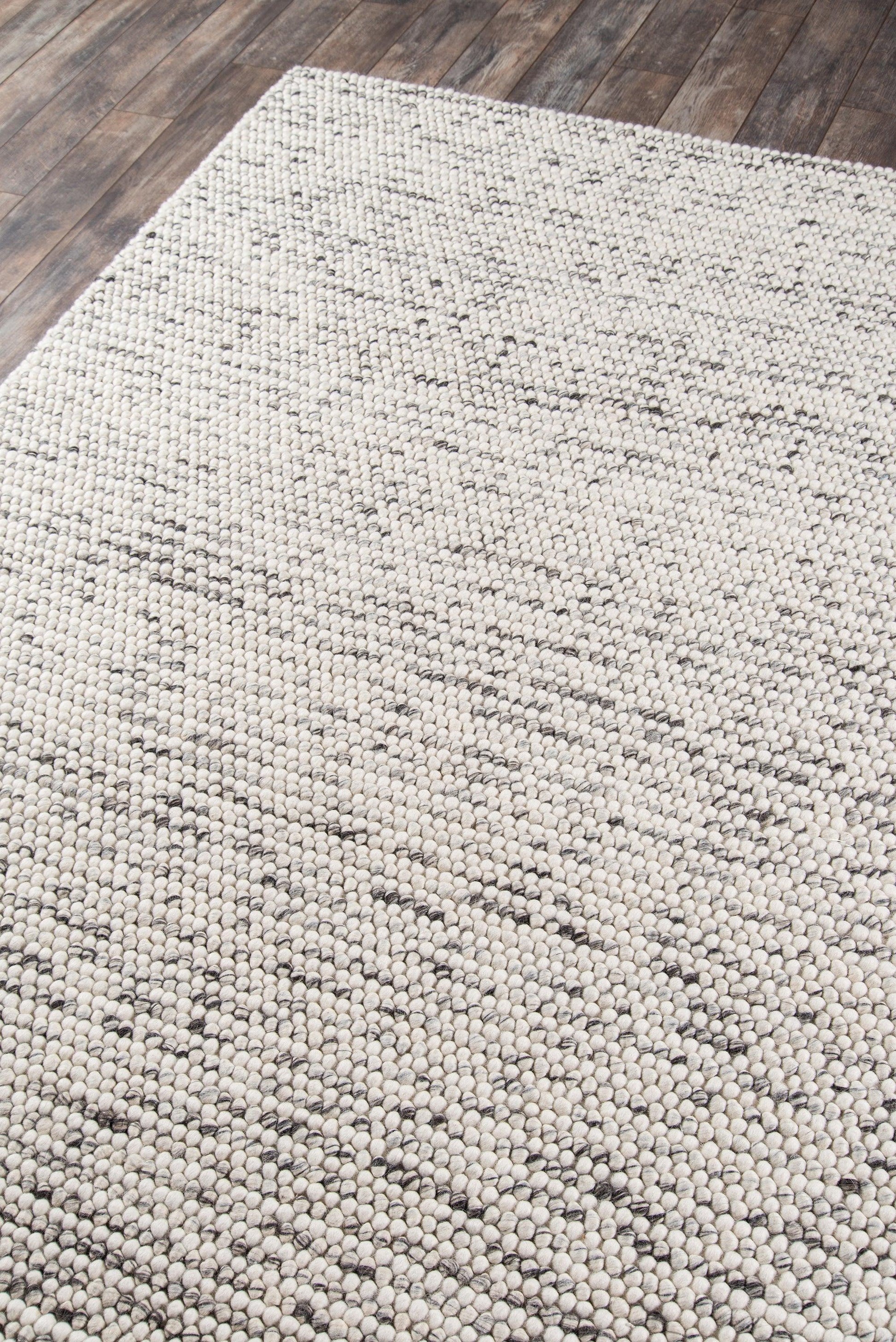 Beige loop-pile rug with subtle geometric motif on a dark wood floor; cozy, neutral home decor.